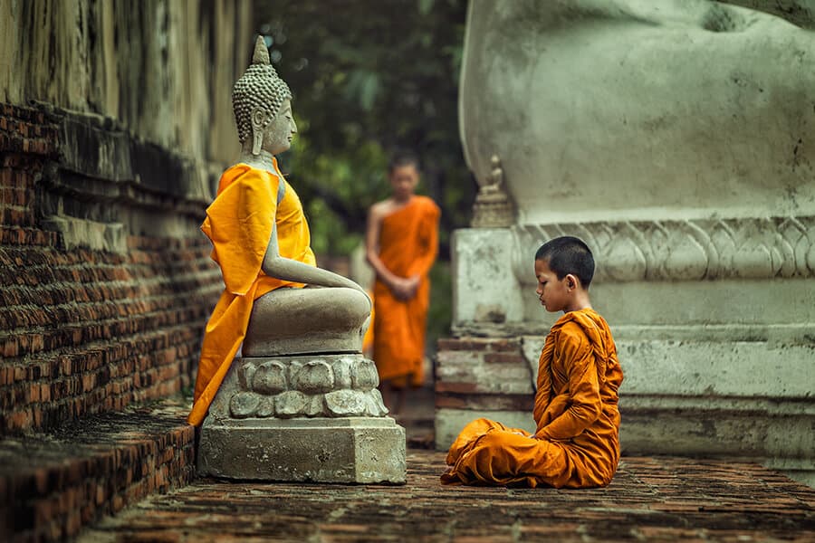 Young Novice monk praying in front of Buddha statue