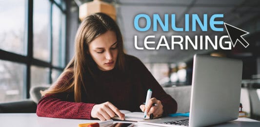 Young student scribing notes while taking an online course