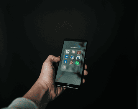 A hand holding out a cellphone with icons.