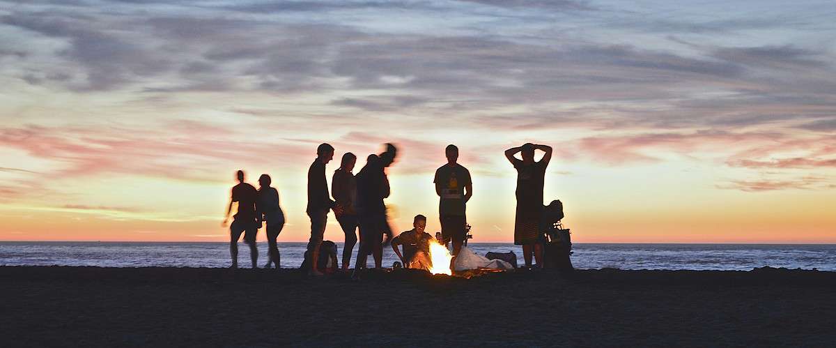A group of people on a beach at sunset