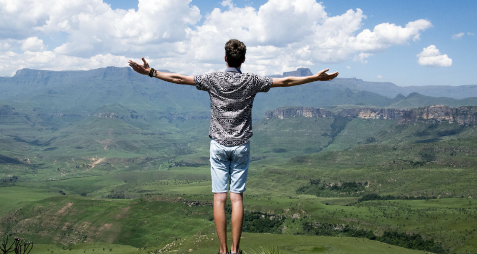 A person standing on a rock and holding their hands outstretched.