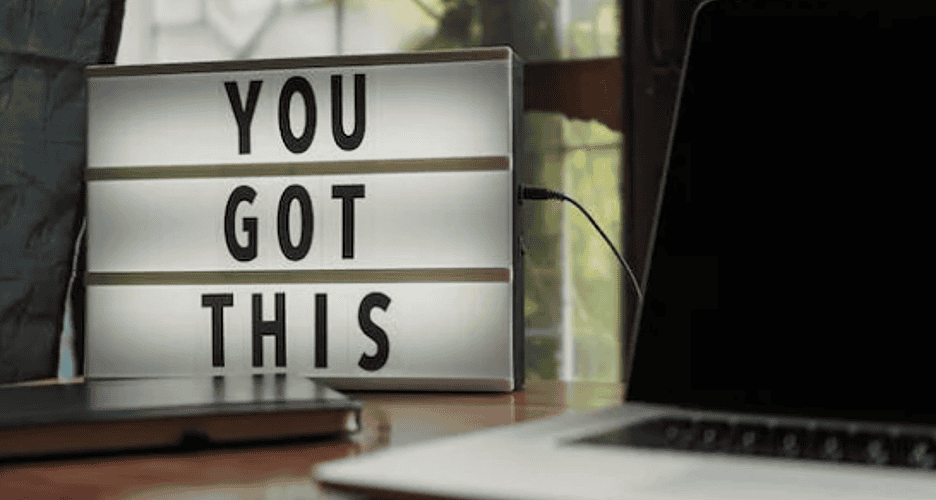 A computer and a sign on a desk.