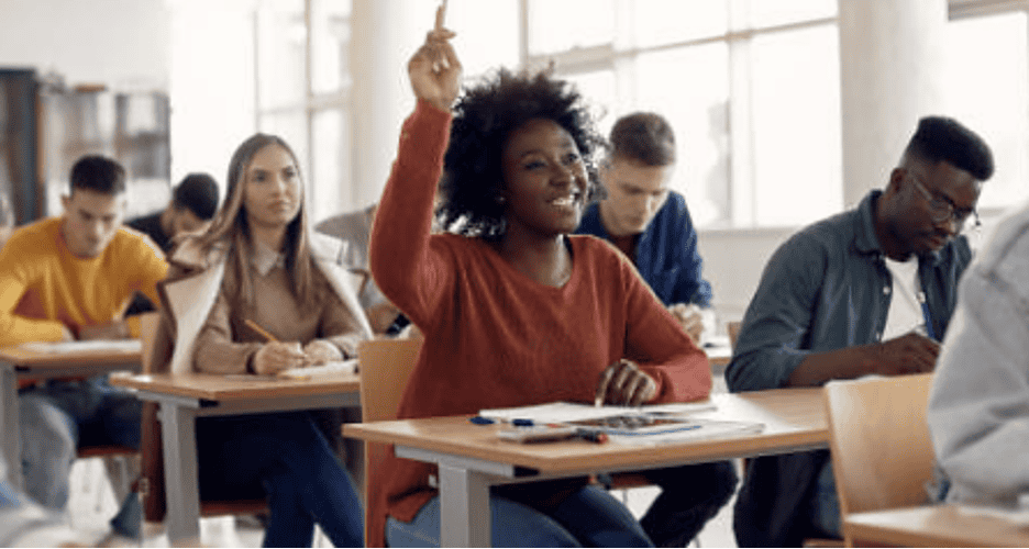 A person in a classroom raises her hand.